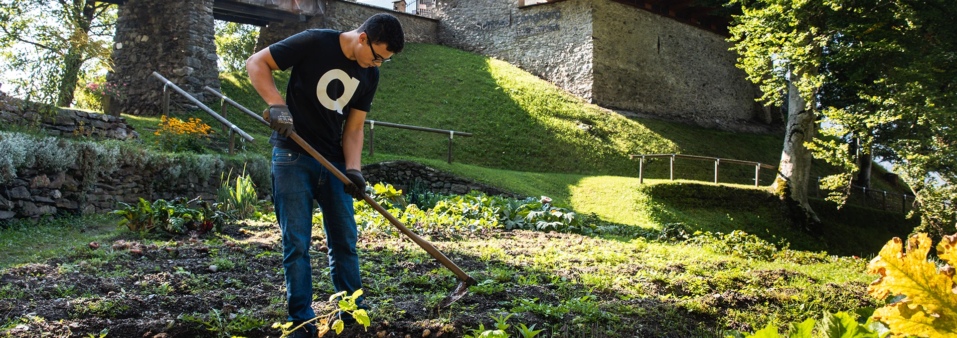 Ein junger Mann harkt im Garten von Schloss Lengberg.