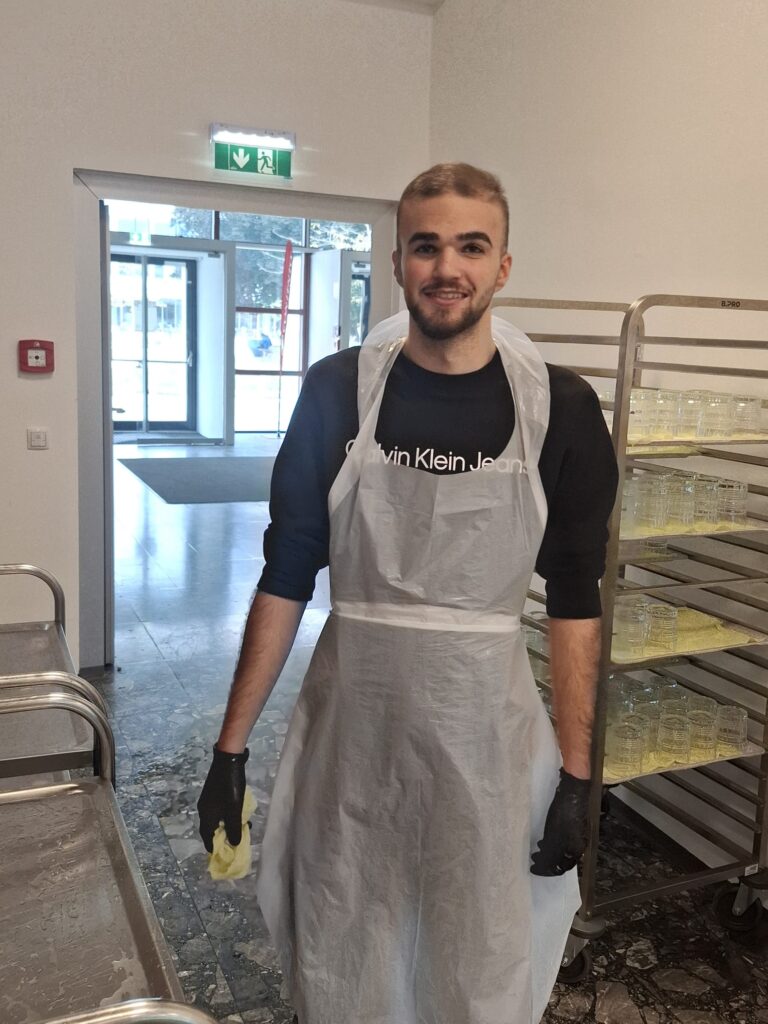 Ein junger Mann mit Dienstkleidung putzt die Arbeitsflächen